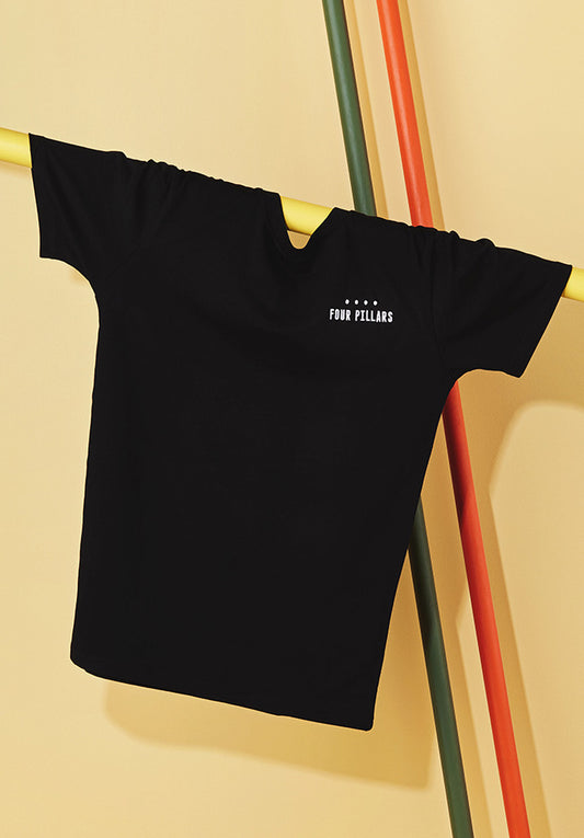 A standard black tshirt with a white embroided Four Pillars Gin logo on the left breast, hanging on a yellow pole.