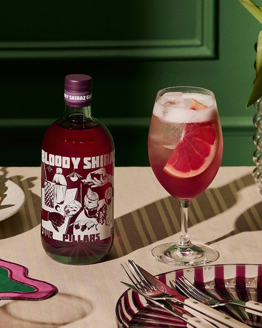 A bottle of the limited edition 2024 Bloody Shiraz Gin from Four Pillars Gin next to a bloody gin spritz cocktail. 