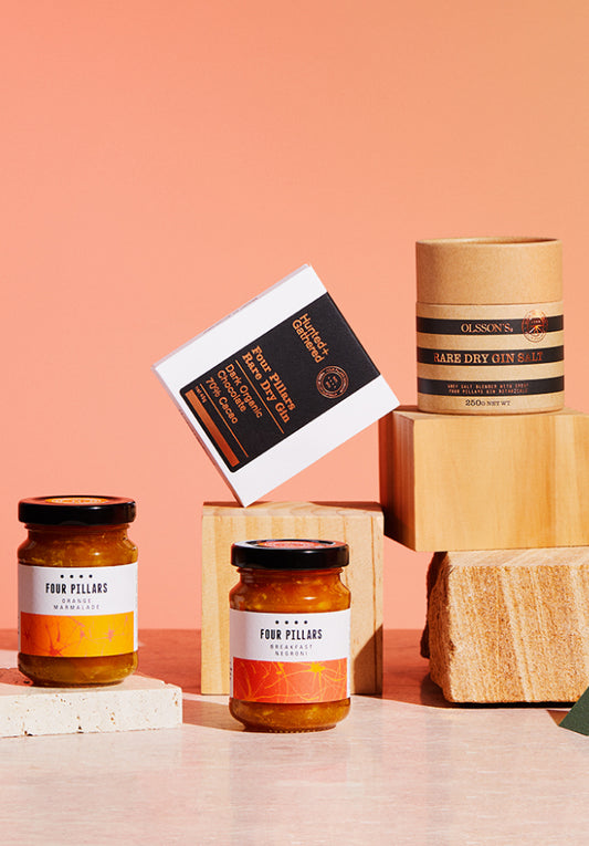 Three jars and a box on wooden blocks against a peach background